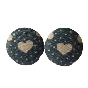 Può includere: Un paio di orecchini in tessuto blu con pois bianchi e motivi a forma di cuore bianchi.