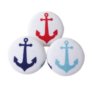 Op de afbeelding: Drie witte stoffen knopen met ankerontwerpen. De ankers zijn rood, blauw en lichtblauw.
