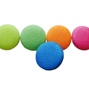 Könnte beinhalten: Fünf bunte runde Knöpfe mit einer strukturierten Oberfläche. Die Knöpfe sind grün, hellgrün, orange, rosa und blau.