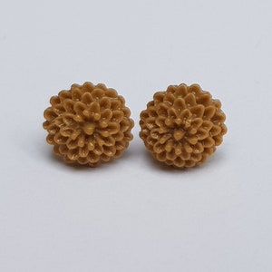 Może przedstawiać: Para brązowych kolczyków w kształcie kwiatu.