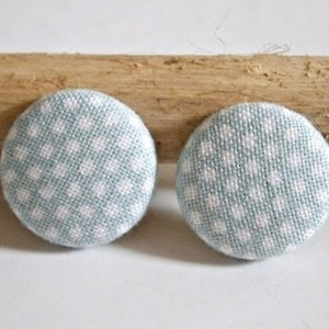 Może przedstawiać: Dwa okrągłe guziki z tkaniny z jasnoniebieskim tłem i białymi kropkami.