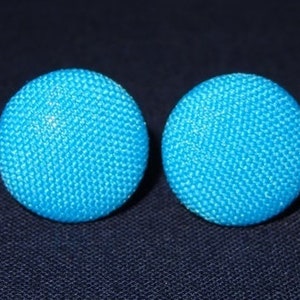 Może przedstawiać: Para jasnoniebieskich, okrągłych kolczyków z fakturowaną powierzchnią.