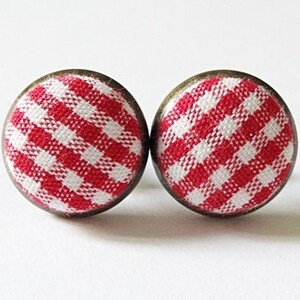 Può includere: Un paio di orecchini in tessuto gingham rosso e bianco con montature in metallo bronzo.