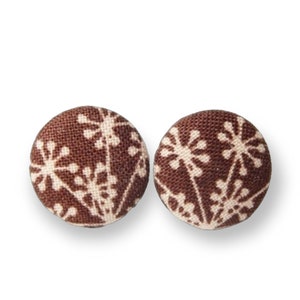 May include: A pair of brown fabric earrings with a white floral pattern.
