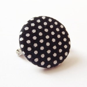 Könnte beinhalten: Schwarze und weiße gepunktete Stoffknopf-Brosche.