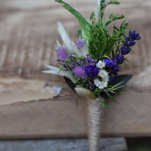 Op de afbeelding: Een klein boeket met paarse en witte bloemen, vastgebonden met touw. Het boeket bevat lavendel, witte wilde bloemen en paarse distel.