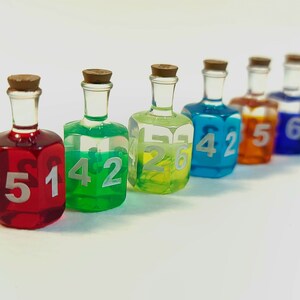 May include: Six small glass bottles with cork stoppers filled with coloured liquids and numbered 3, 4, 2, 5, 4, and 6.