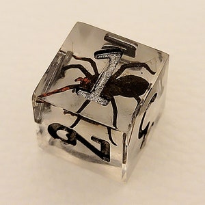 May include: A clear cube with a black spider encased in resin. The cube has the number "1" printed on one side.