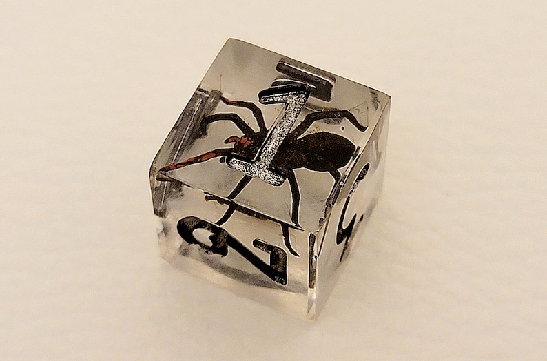 May include: A clear cube with a black spider encased in resin. The cube has the number "1" printed on one side.