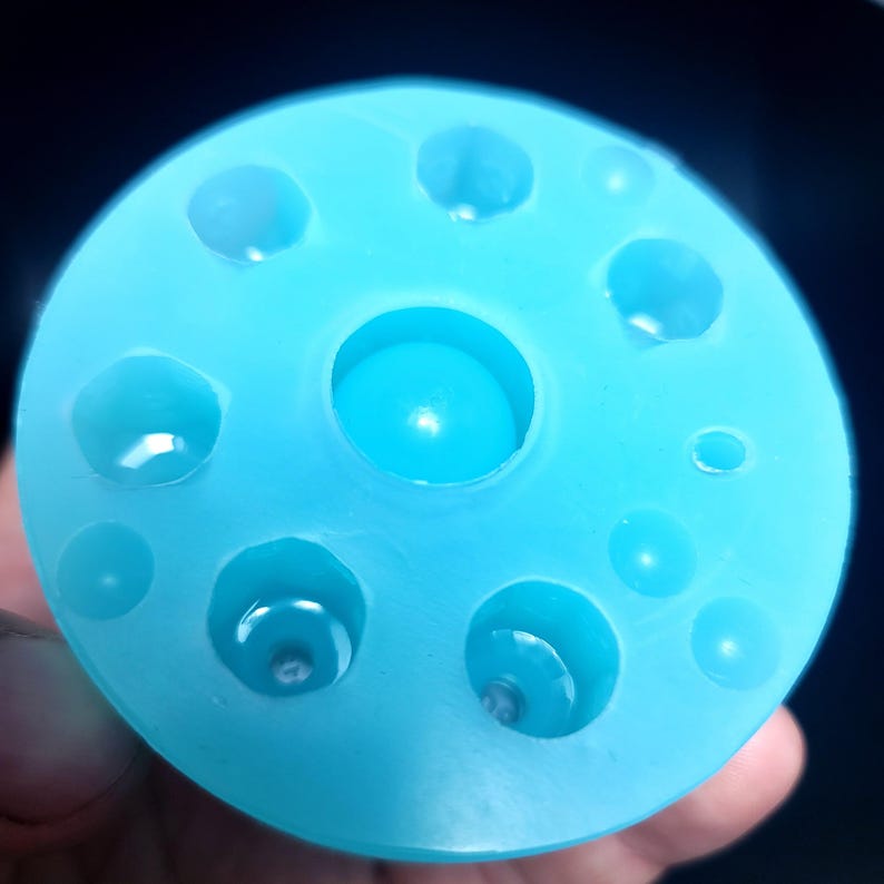 May include: A light blue silicone mold with multiple circular depressions of varying sizes. The mold is designed for creating resin crafts.
