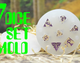May include: A white, round mold for making a set of seven dice. The mold has six impressions of dice, and one impression of a d20 die. The mold is sitting on a bed of brown straw.