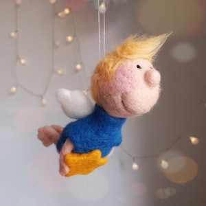 Könnte beinhalten: Ein Filz-Engel-Anhänger mit blonden Haaren, blauer Kleidung und weißen Flügeln, der einen gelben Stern hält.