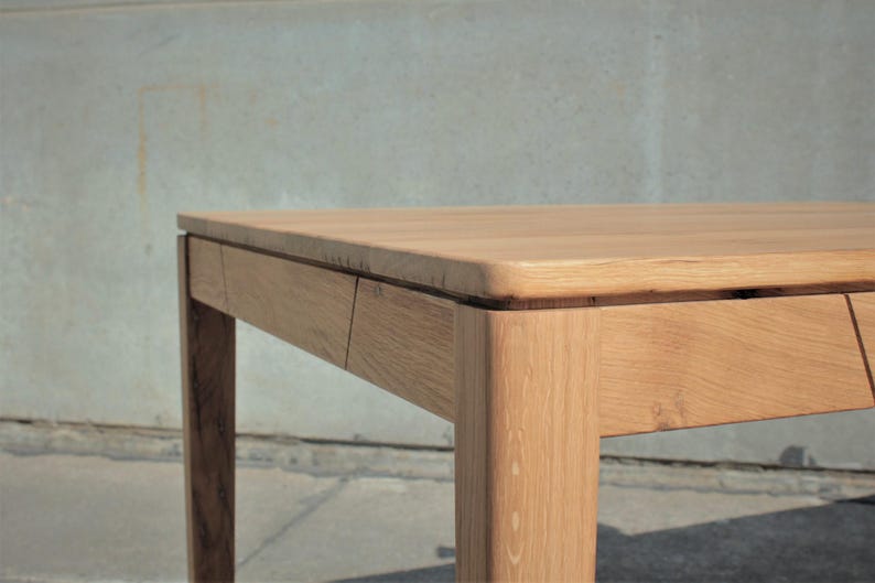 May include: A light brown wooden table with a rectangular top and four square legs. The table has a natural wood grain finish and appears to be made of solid wood. The table's dimensions are not visible in the image.