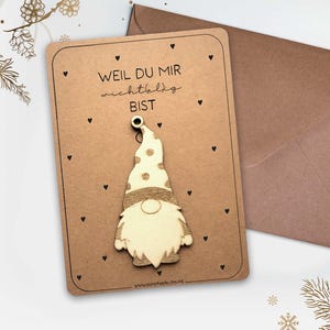 Könnte beinhalten: Braune Grußkarte mit Holzgnom-Ornament und braunem Umschlag. Die Karte trägt den Text "WEIL DU MIR wichtig BIST" und kleine schwarze Herzen. Der Gnom hat einen weißen und beigefarbenen Hut.