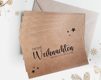 May include: A stack of brown kraft paper Christmas cards with the text "Frohe Weihnachten und ein gutes neues Jahr" printed in black. The cards are decorated with small black stars.