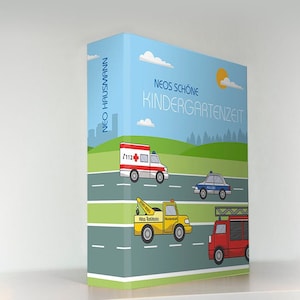 Könnte beinhalten: Ein blauer Ordner mit dem Text "NEO'S SCHÖNE KINDERGARTENZEIT" und dem Namen "NEO HAUSMANN" auf dem Rücken. Die Vorderseite zeigt eine Comic-Illustration einer Straße mit einem Krankenwagen, einem Polizeiauto, einem Abschleppwagen und einem Feuerwehrauto.
