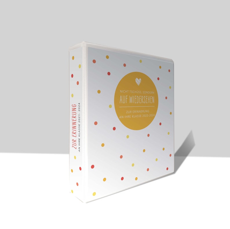 May include: White binder with a yellow circle and the text "Nicht Tsch&uuml;ss, sondern Auf Wiedersehen" and "Zur Erinnerung an Ihre Klasse 2020-2024". The binder has red and yellow polka dots.