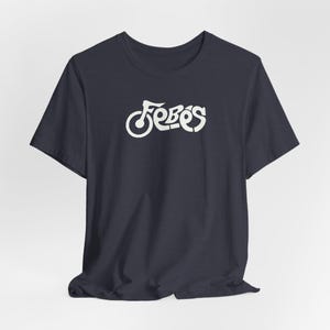 May include: Navy blue t-shirt with the word "Febos" in a stylized, white font across the chest. The design features a unique, cursive-like lettering style, making it a distinctive apparel item. The shirt is made of a soft material.