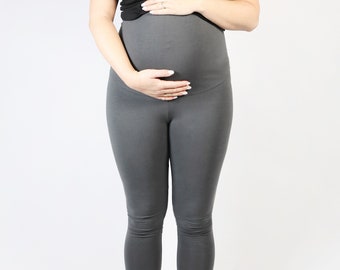 May include: A pregnant person wearing a black tank top and gray maternity leggings.