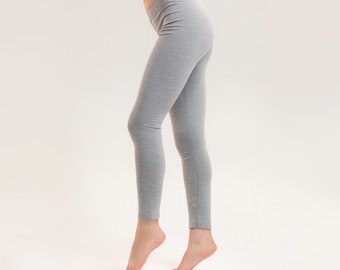 May include: A pair of grey leggings on a person's legs. The leggings are made of a soft, stretchy material and have a comfortable fit.