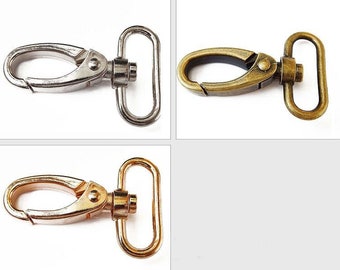 May include: Two metal swivel clasps, one silver and one gold, with a D-ring on one end and a hook on the other. These clasps are commonly used for attaching straps, chains, or other accessories.