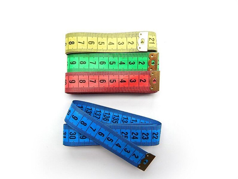 K&ouml;nnte beinhalten: Drei Ma&szlig;b&auml;nder, eines gelb, eines gr&uuml;n und eines rot, liegen &uuml;bereinander gestapelt. Ein blaues Ma&szlig;band liegt daneben aufgerollt.