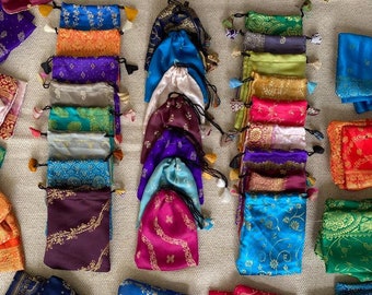 May include: Assortment of colorful drawstring pouches with intricate patterns and gold accents. The pouches are made of silk and are perfect for storing small items like jewelry, coins, or tea.