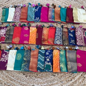 May include: A collection of 30 small drawstring pouches made of colorful patterned fabric. The pouches are lined up in rows and are all different colors and patterns.