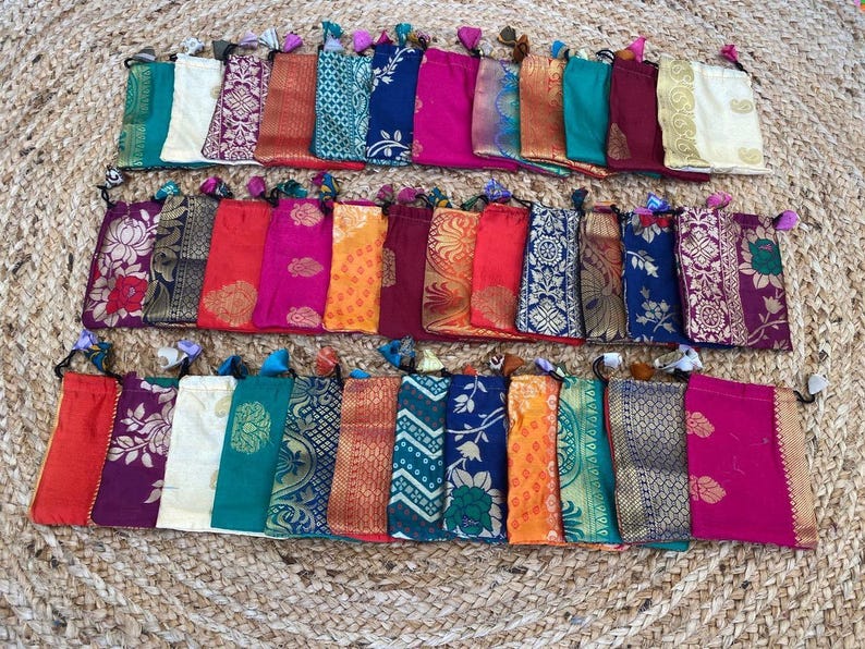 May include: A collection of 30 small drawstring pouches made of colorful patterned fabric. The pouches are lined up in rows and are all different colors and patterns.