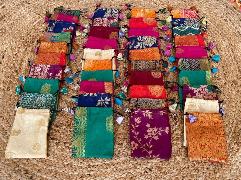 May include: A collection of 20 small, colorful drawstring bags made from fabric with intricate patterns. The bags are arranged in rows and have tassels on the drawstrings.
