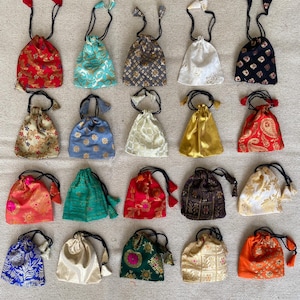 May include: Twenty-four small drawstring bags in various colors and patterns, including red, blue, green, gold, and white. The bags are made of fabric and have a tassel on the drawstring.
