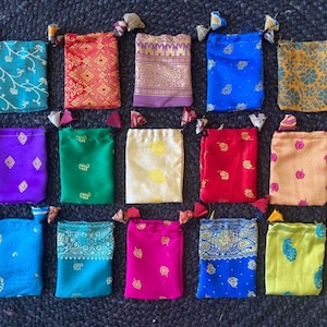 May include: Assortment of 15 small drawstring bags made from colorful patterned fabric. The bags are approximately 4 inches wide and 5 inches tall.