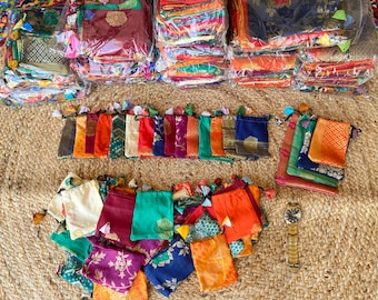 May include: A collection of colorful fabric pouches with drawstrings. The pouches are made from a variety of fabrics, including silk, cotton, and velvet. They are arranged in rows on a woven mat.