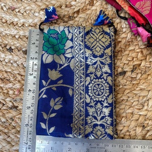 May include: A small blue pouch with gold embroidery and a floral pattern. The pouch has a drawstring closure and is made of a soft, luxurious fabric.