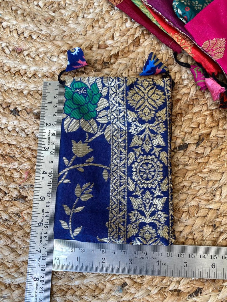May include: A small blue pouch with gold embroidery and a floral pattern. The pouch has a drawstring closure and is made of a soft, luxurious fabric.