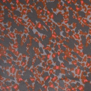Op de afbeelding: Een close-up van een stof met een grijze en oranje luipaardprint.