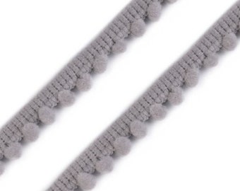 May include: Grey pom-pom trim with small, fluffy balls along the edge. The trim is shown folded in half.