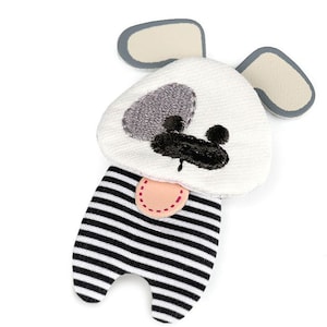 Op de afbeelding: Een wit en zwart gestreept stoffen hondenspeelgoed met grijze en zwarte geborduurde gezichtskenmerken. Het speelgoed heeft een roze tong en grijze oren.