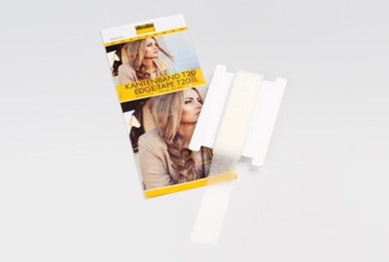 Peut inclure: Ruban adh&eacute;sif blanc pour extensions de cheveux. Le ruban est emball&eacute; dans une bo&icirc;te blanche avec le texte "KANTENBAND T20 EDGE TAPE T20" imprim&eacute; dessus.
