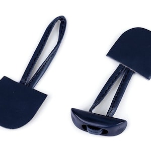 May include: Two navy blue leather toggles with a plastic button. The toggles have a loop at the top and a rounded bottom.