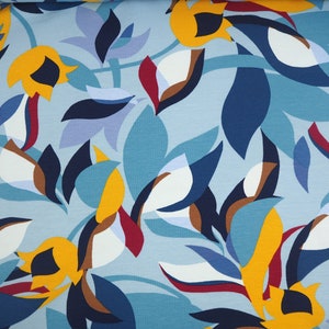 Op de afbeelding: Abstracte bloemenprintstof in tinten van blauw, geel, wit en bruin. De stof heeft een herhalend patroon van gestileerde bloemen en bladeren.