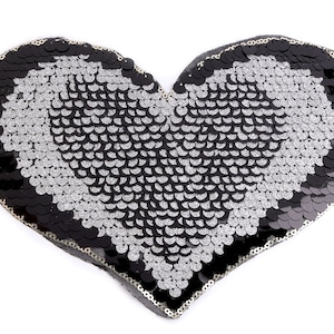 Könnte beinhalten: Ein herzförmiger Pailletten-Patch in Schwarz und Silber. Die Pailletten sind in einem Muster angeordnet, das eine Herzform erzeugt. Der Patch ist perfekt, um jedem Projekt einen Hauch von Glanz zu verleihen.