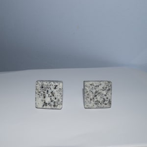 May include: Two square-shaped, gray and white granite coasters.