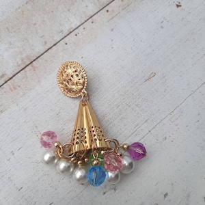 Op de afbeelding: Gouden oorbel met een kegelvormige hanger en hangende kralen. De kralen zijn wit, roze, blauw en groen.