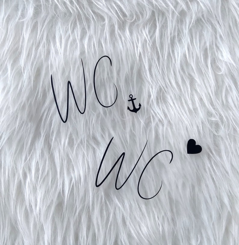 May include: White fluffy background with the text "WC" written twice in black cursive. A small black anchor symbol is between the first two letters of the first "WC" and a small black heart is to the right of the second "WC".