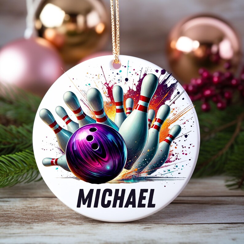 May include: A round, white bowling-themed ornament with a vibrant design. It features a purple and black bowling ball, white bowling pins with red stripes, and the name "MICHAEL" in bold black letters. The ornament hangs from a gold chain.