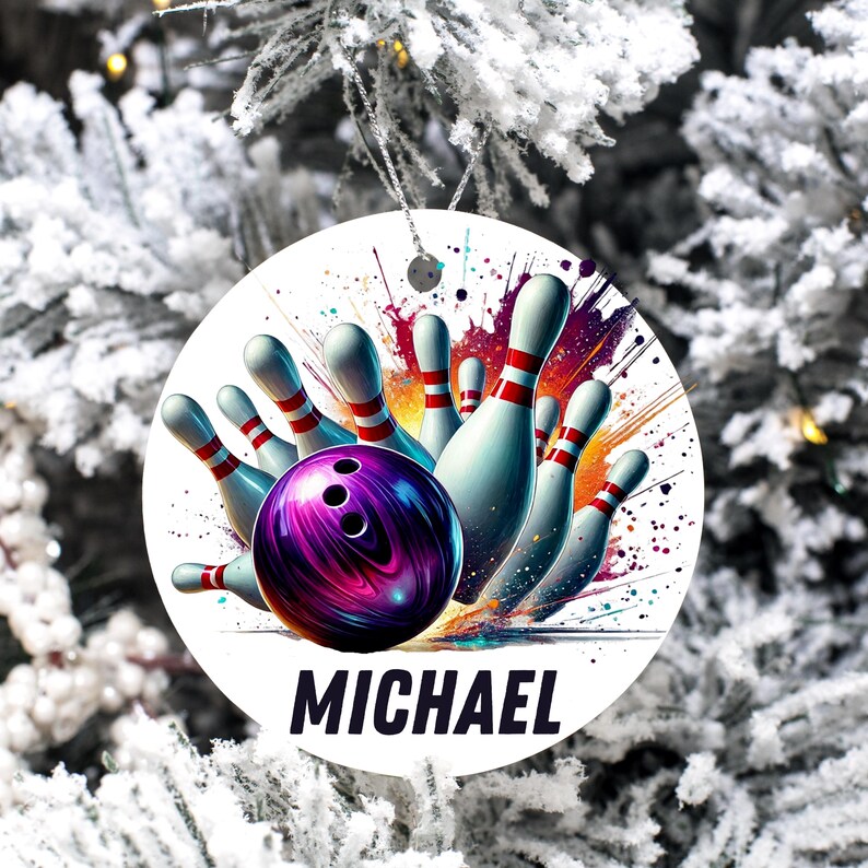 May include: A round Christmas ornament featuring a bowling scene with a purple bowling ball and white bowling pins with red stripes. The name "MICHAEL" is printed in bold black letters at the bottom.