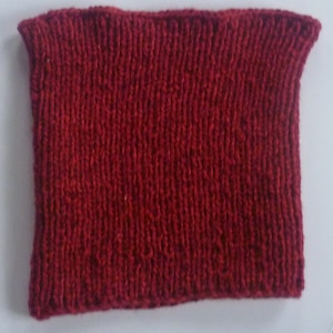 Peut inclure: Un bandeau en tissu rouge bordeaux tricoté de près. Le bandeau est fait d'un fil doux et texturé.