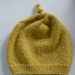Puede incluir: Un gorro de punto amarillo con un nudo en la parte superior.