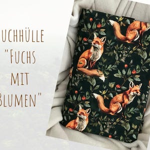 Könnte beinhalten: Eine Buchhülle mit dunkelgrünem Hintergrund und einem sich wiederholenden Muster aus orangefarbenen Füchsen, grünen Blättern und kleinen roten Blumen. Der Text "BUCHHÜLLE "FUCHS MIT BLUMEN"" ist auf der linken Seite aufgedruckt.